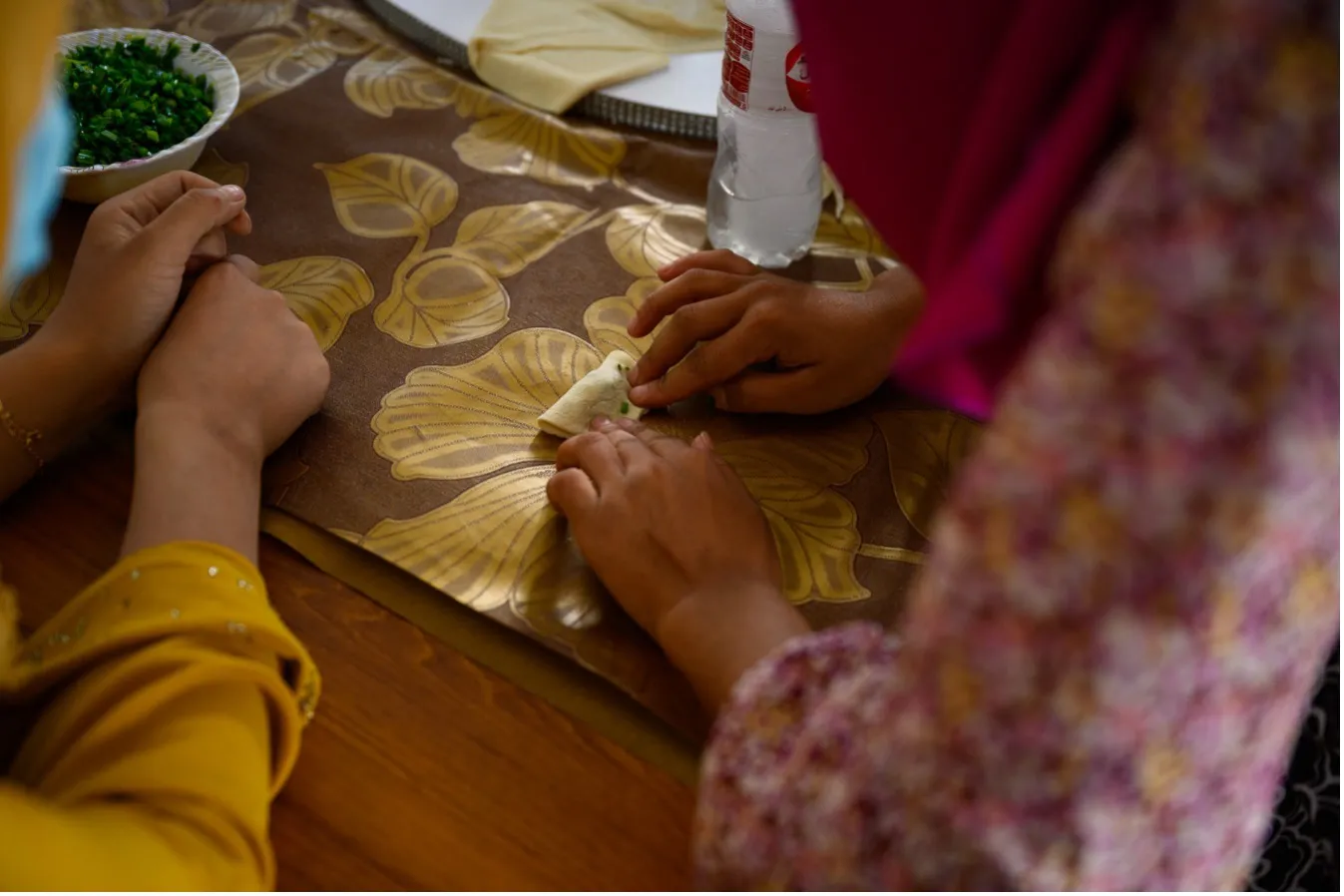 Close-up on the hands of two women preparing food on a table.