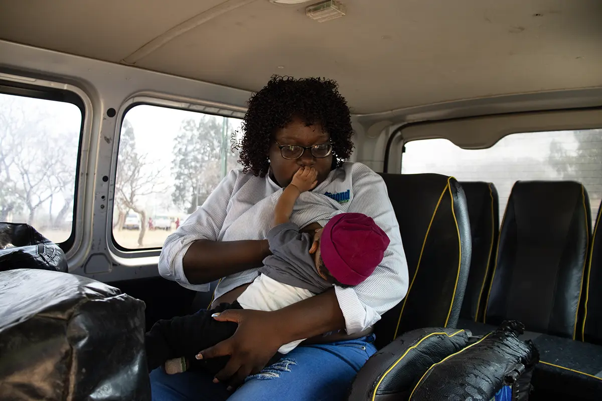 A woman sits in a car while breastfeeding her baby.