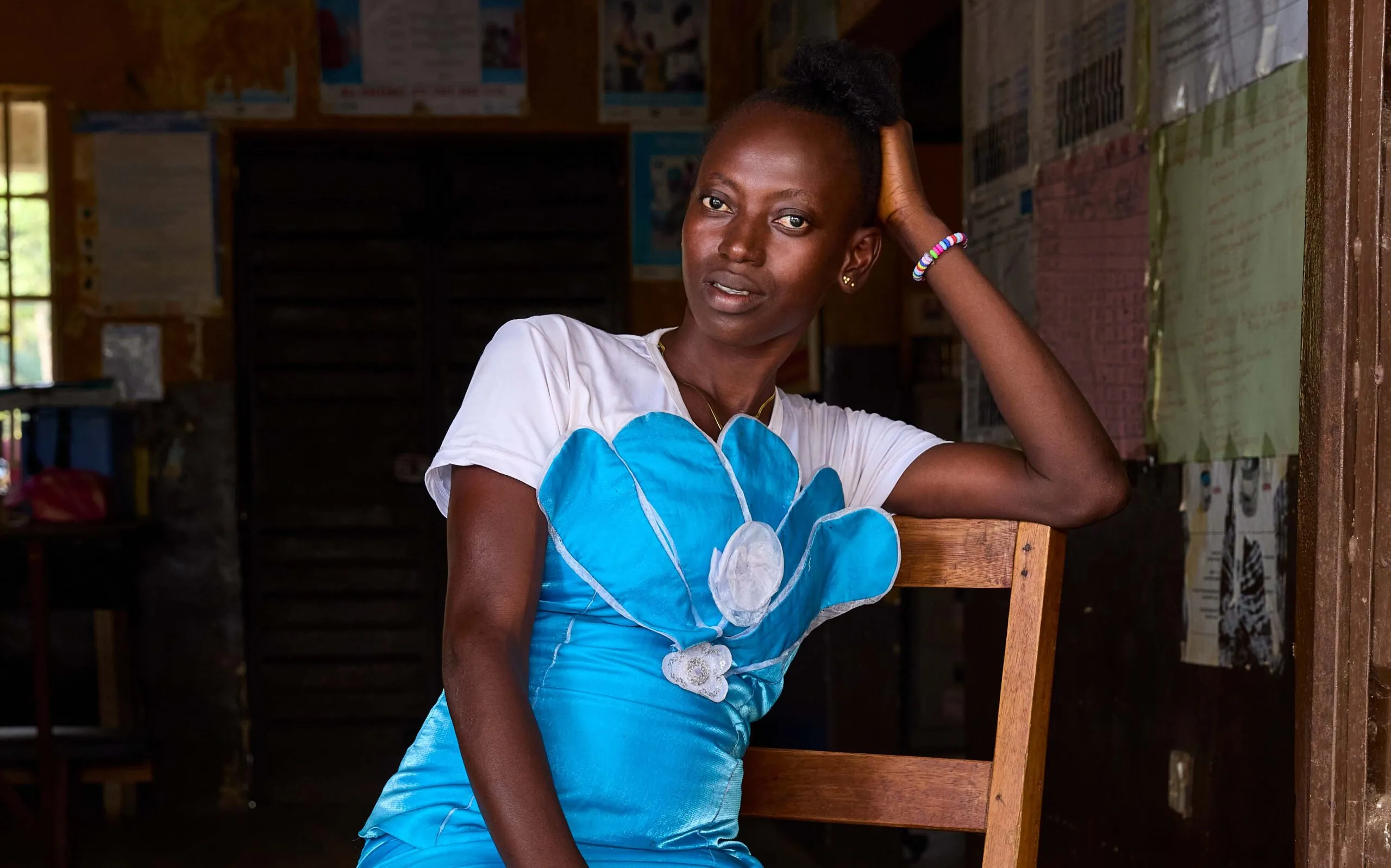 Medium-format portrait of woman in bright blue dress, resting head on her arm, looking at camera.