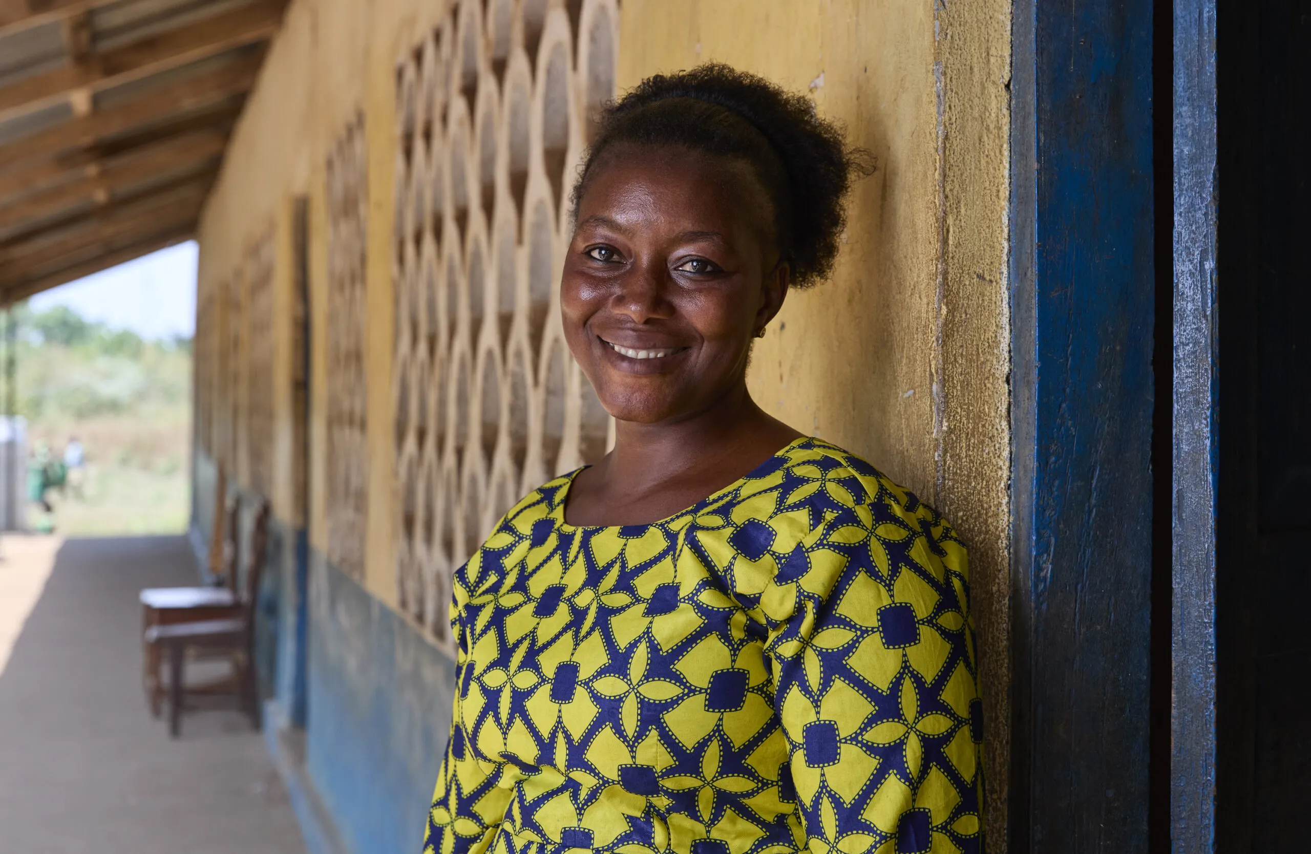 Portrait of a woman standing in front of a school.