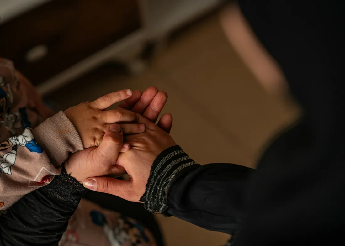 A woman's hand holding the hand of a child.