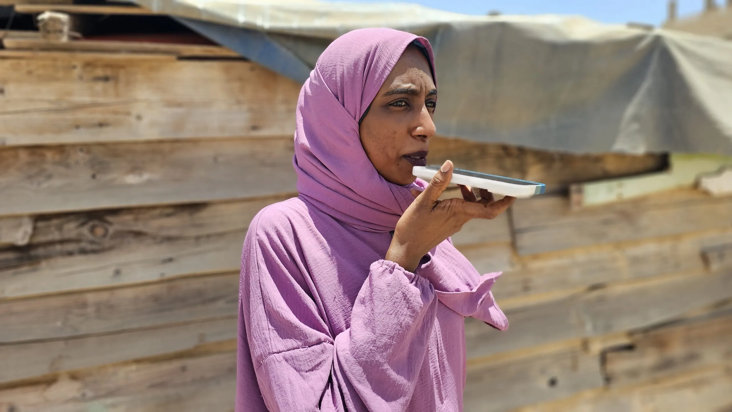 A humanitarian worker in a pink head scarf speaks into her phone.