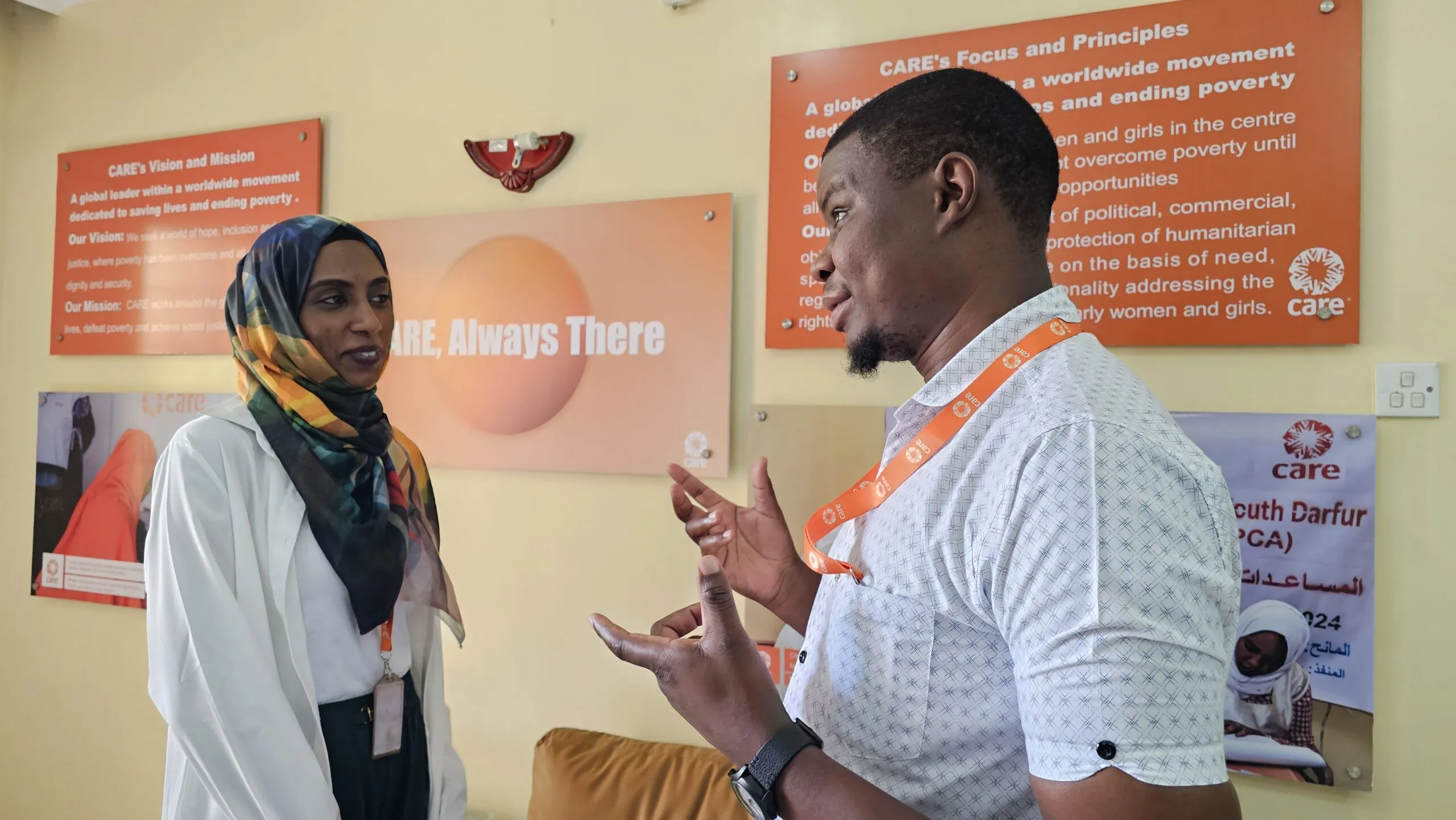 Two smiling humanitarians stand together, discussing work.